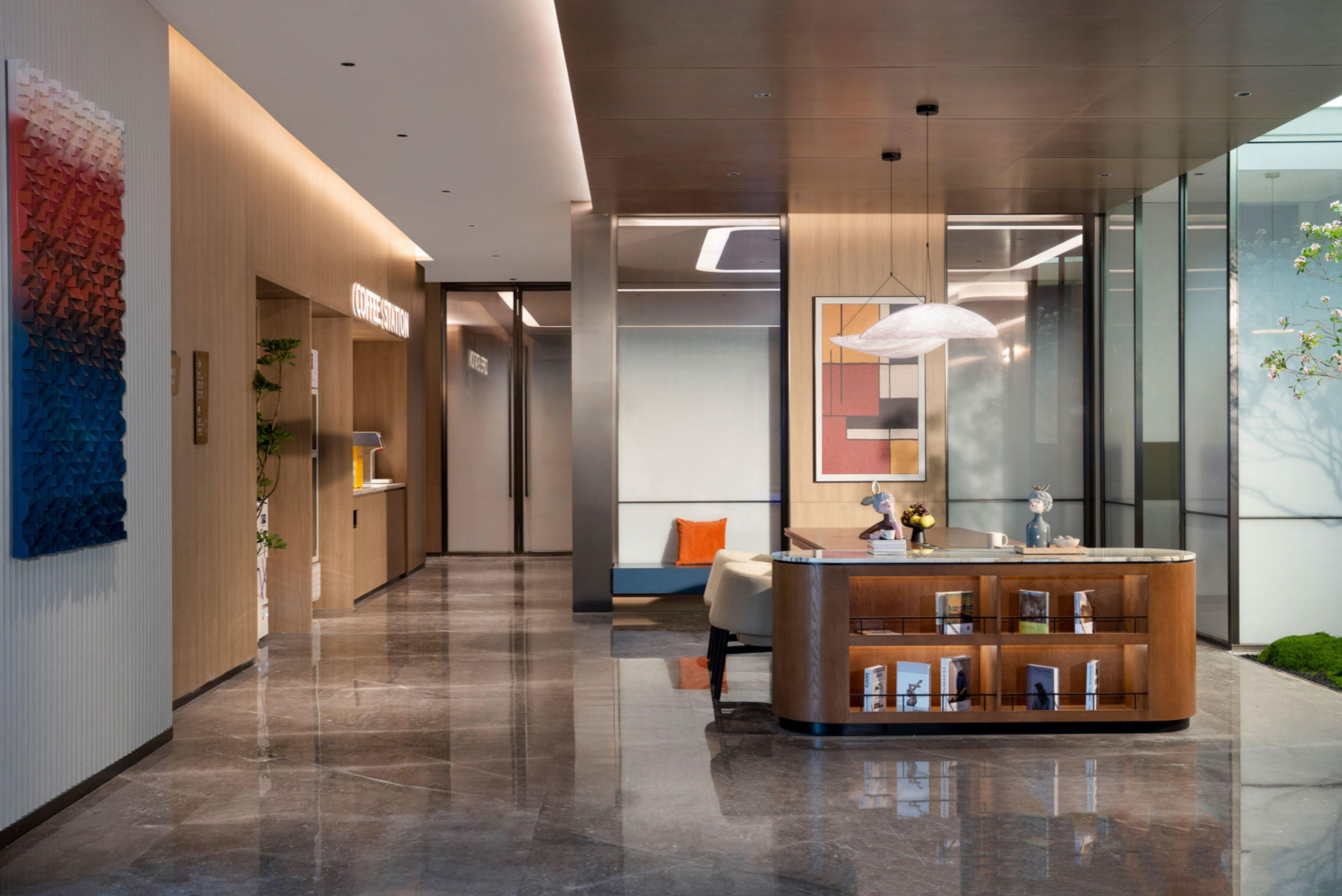 A modern lobby with a reception desk, seating area, and a coffee station.