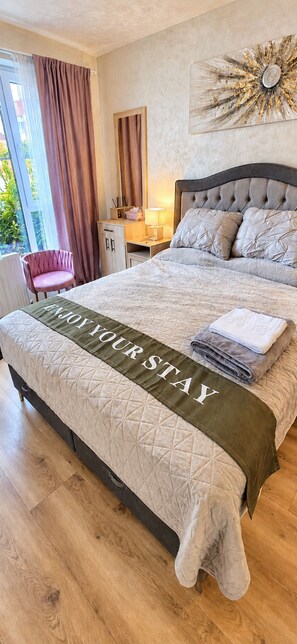 A hotel room with a bed, a bedside table, a chair, and a view of the outdoors.