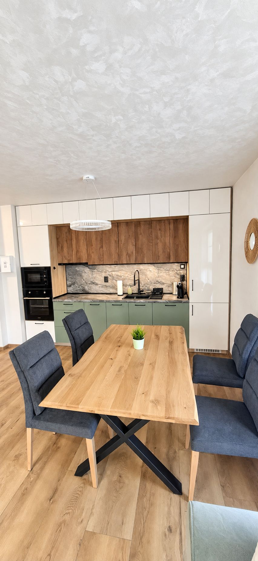 Une cuisine moderne avec une table à manger en bois, deux chaises et un four encastré.