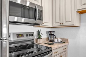 Eine Küche mit Edelstahl-Kühlschrank, Mikrowelle, Backofen und Kaffeemaschine auf der Arbeitsfläche.