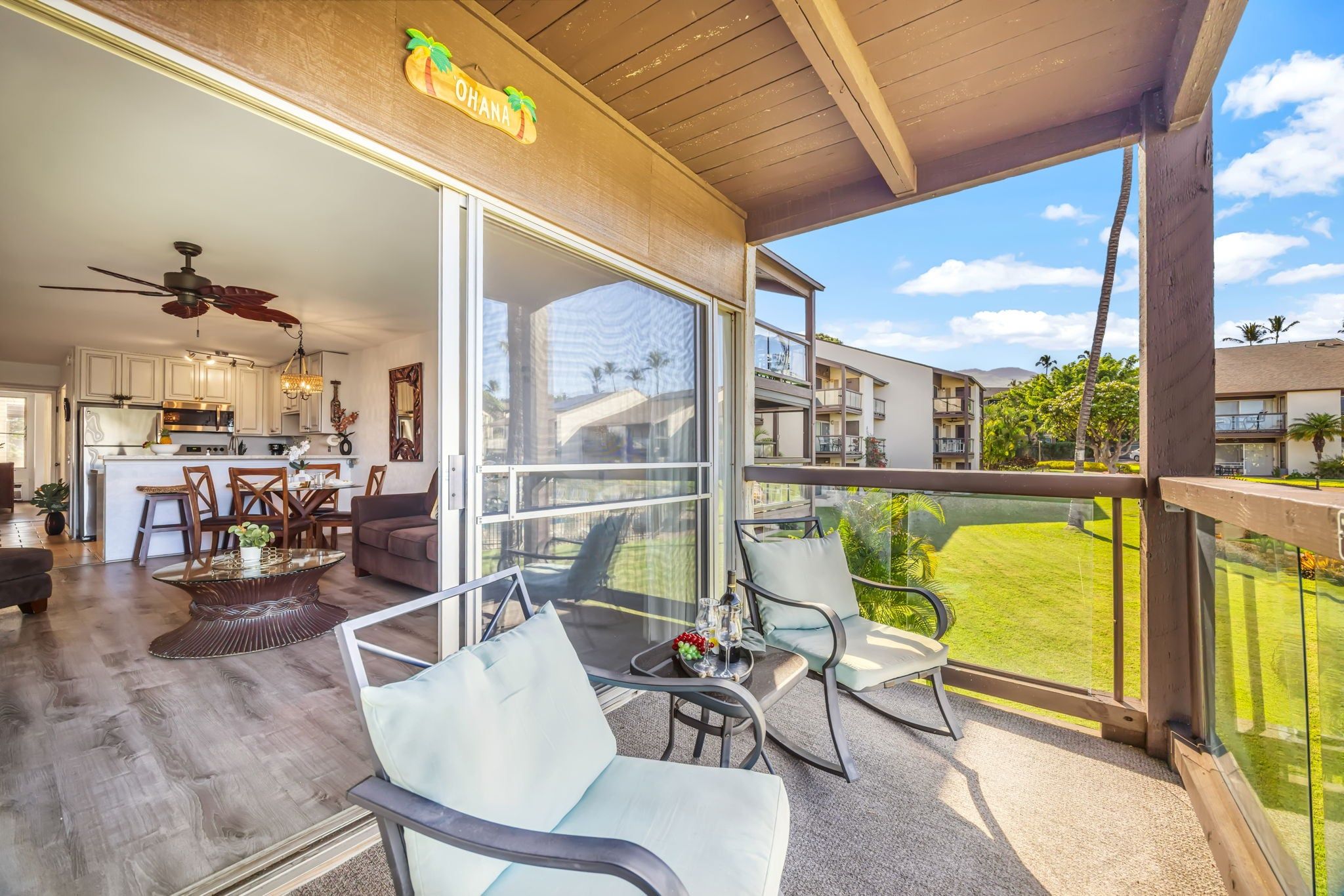 A spacious balcony with a clear view of a lush garden and a modern kitchen visible through the glass doors.