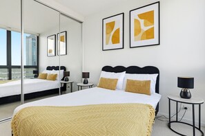 A hotel room with a large bed, bedside tables, a mirror, and artwork on the wall. - Waterfront Escape 2BR Apt w/Pool, Gym & Parking (Docklands)