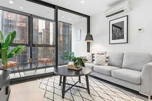 Ein modernes Wohnzimmer mit einer Couch, einem Couchtisch und einem großen Fenster mit Blick auf die Stadt.