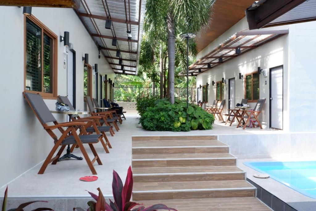 Un espacio al aire libre cubierto con asientos, piscina y una escalera que sube a un nivel superior.