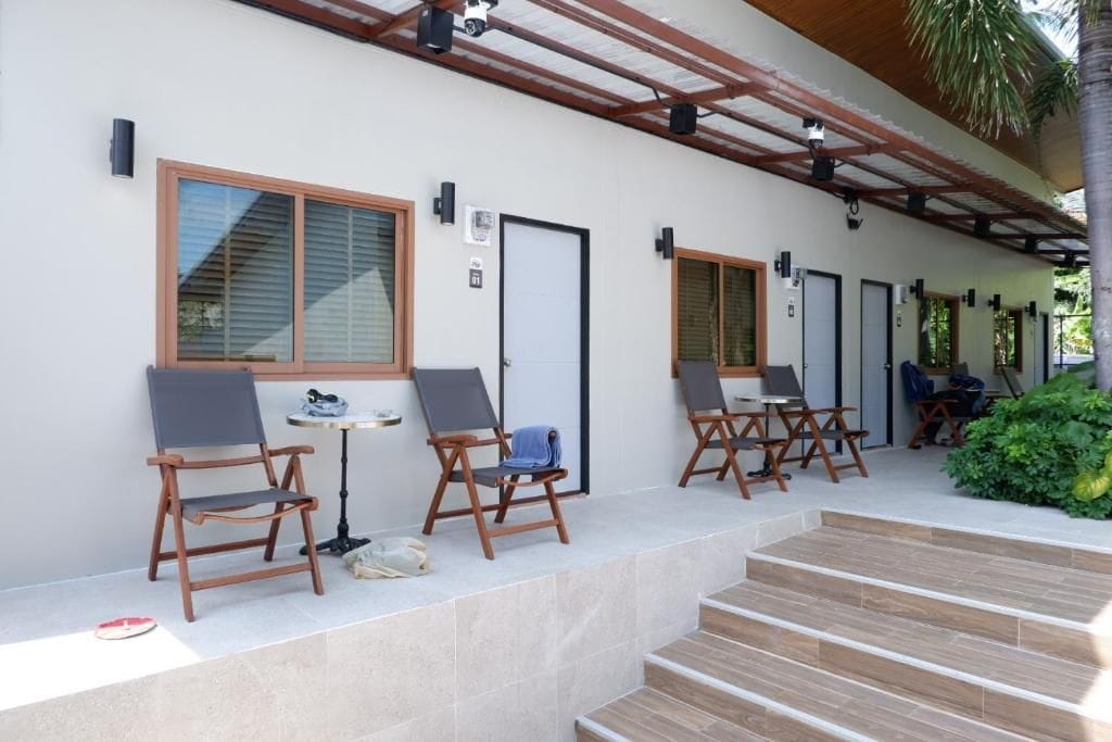 Un espace extérieur aménagé avec des sièges, comprenant plusieurs chaises et tables, un escalier menant à un niveau supérieur et une porte avec une enseigne.