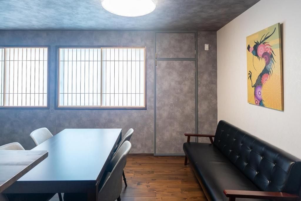 Une salle de conférence avec une longue table, des chaises, un canapé et un tableau accroché au mur.