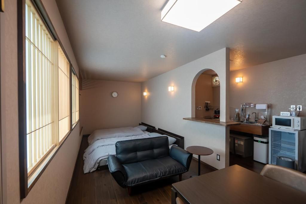Una habitación compacta con cama, sofá, una mesita, microondas y lavamanos.