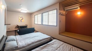 A hotel room with two beds, a desk, and a window with blinds. - Dragon Inn Nikko (nikko)
