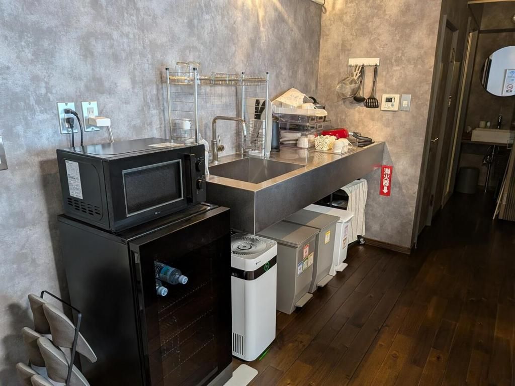 Una kitchenette compacta con microondas, lavamanos y espacios de almacenamiento.