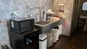 A compact kitchenette with a microwave, sink, and storage units. - Dragon Inn Nikko (nikko)