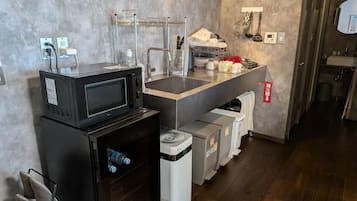 Una kitchenette compacta con microondas, lavamanos y espacios de almacenamiento.