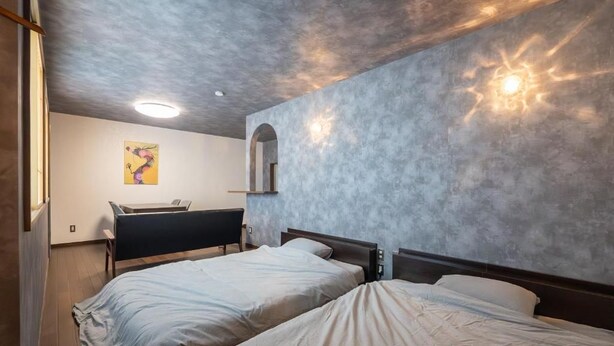 A bedroom with two beds, a desk, and a wall-mounted mirror. - Dragon Inn Nikko (nikko)