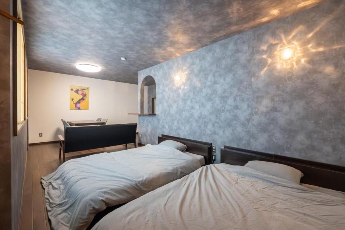 A bedroom with two beds, a desk, and a wall-mounted mirror.
