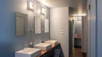 Un baño moderno con tres lavamanos, espejos y un mueble de tocador de madera.