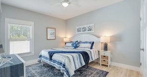 A bedroom with a bed, bedside tables, a desk, and a ceiling fan. - 4BR Home with Fenced Yard & Grill (Panama City Beach)