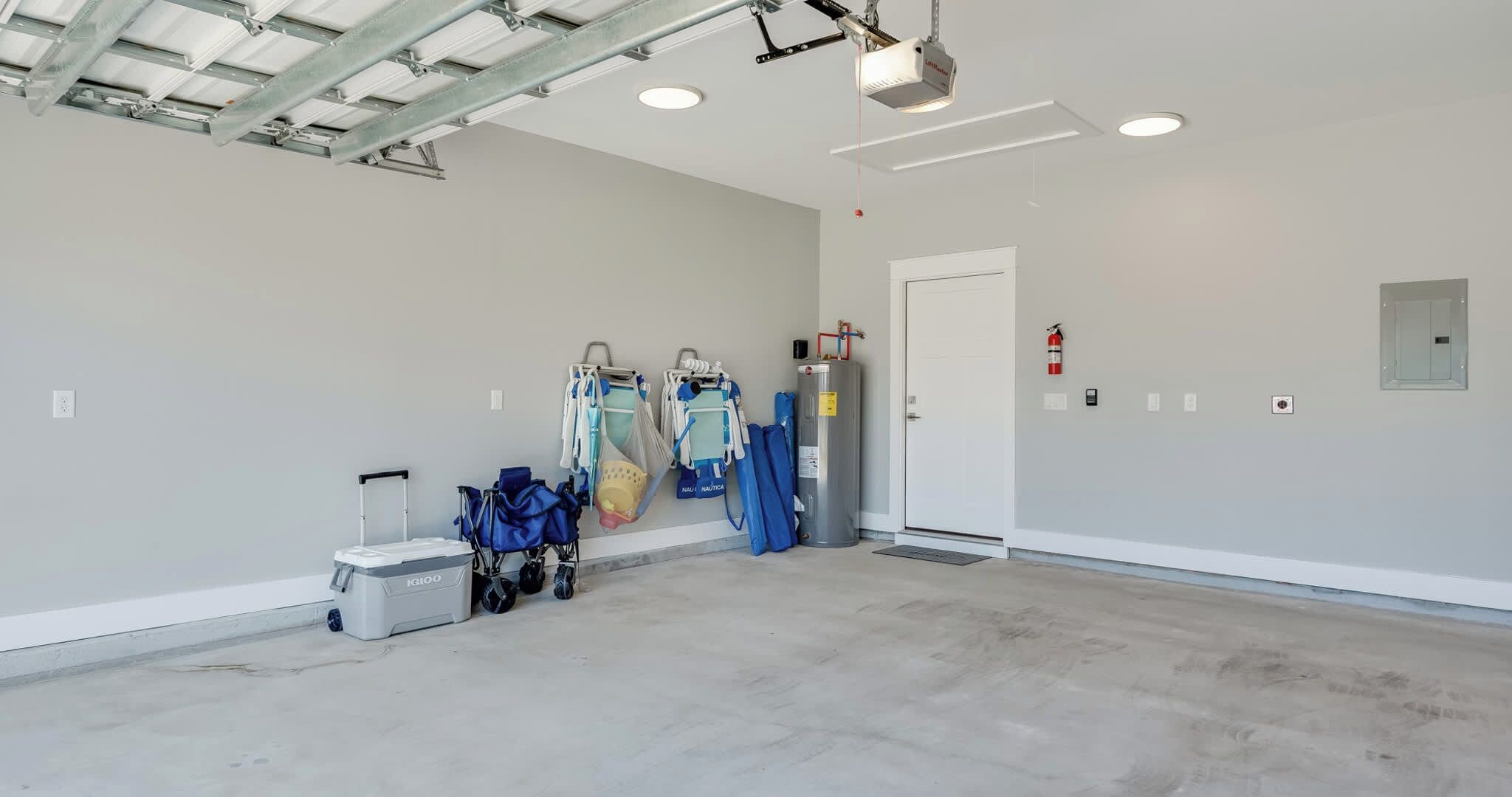 A clean, empty room with a ceiling-mounted projector, a fire extinguisher, and a water heater.