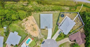 An aerial view of a residential area with multiple houses, a swimming pool, and a tennis court. - 4BR Home with Fenced Yard & Grill (Panama City Beach)