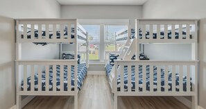 Quarto com beliches, janela com persianas e vista para o exterior.