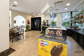 Un restaurante con zona de bar, exhibición de helado de cucurucho y vistas al exterior a través de amplios ventanales.