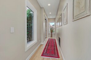A hallway with a red carpet, large windows, and framed artwork on the walls. - Spacious 5-bedroom house in charming guard gated golf course community! (Las Vegas)