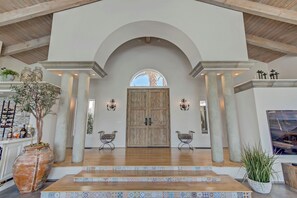 A spacious foyer with a large wooden door, two chairs, a tiled floor, and a potted plant. - Spacious 5-bedroom house in charming guard gated golf course community! (Las Vegas)