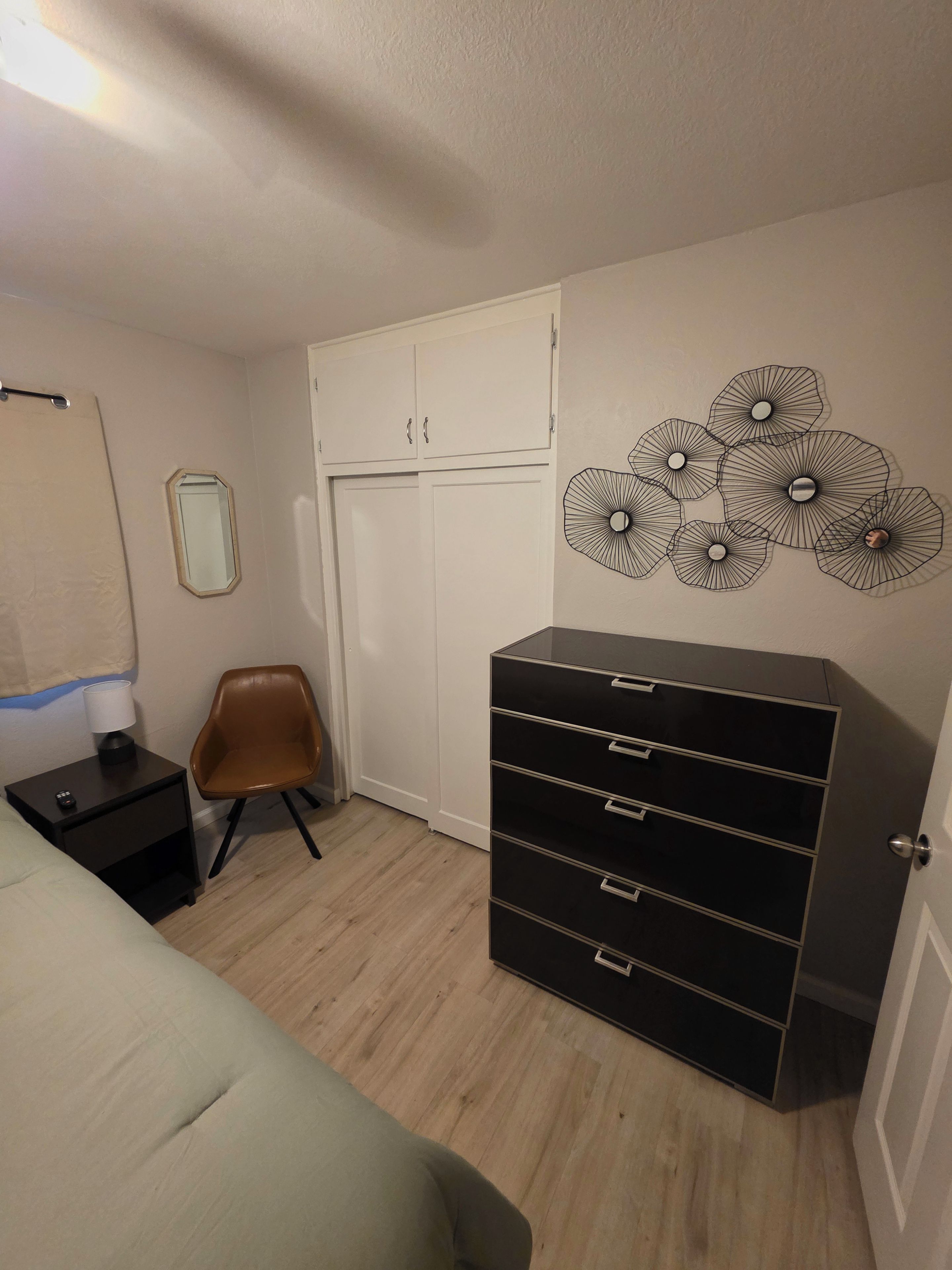 Ein Schlafzimmer mit Bett, Kommode, Stuhl, Kleiderschrank und Wanddekoration.