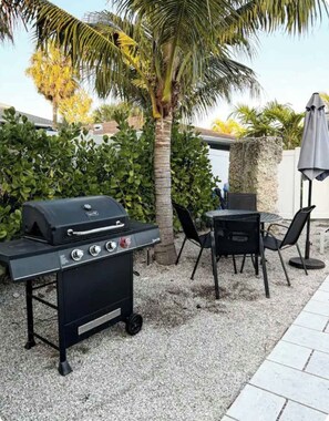 Eine Außenpatio mit Grill, Stühlen und Tisch.