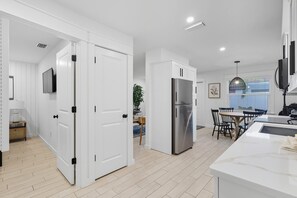 Eine moderne Küche mit weißen Schränken, einem Edelstahlkühlschrank und einem Essbereich mit Tisch und Stühlen.