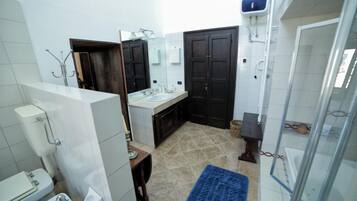 Une salle de bain comprenant des toilettes, un lavabo, un miroir et une douche.