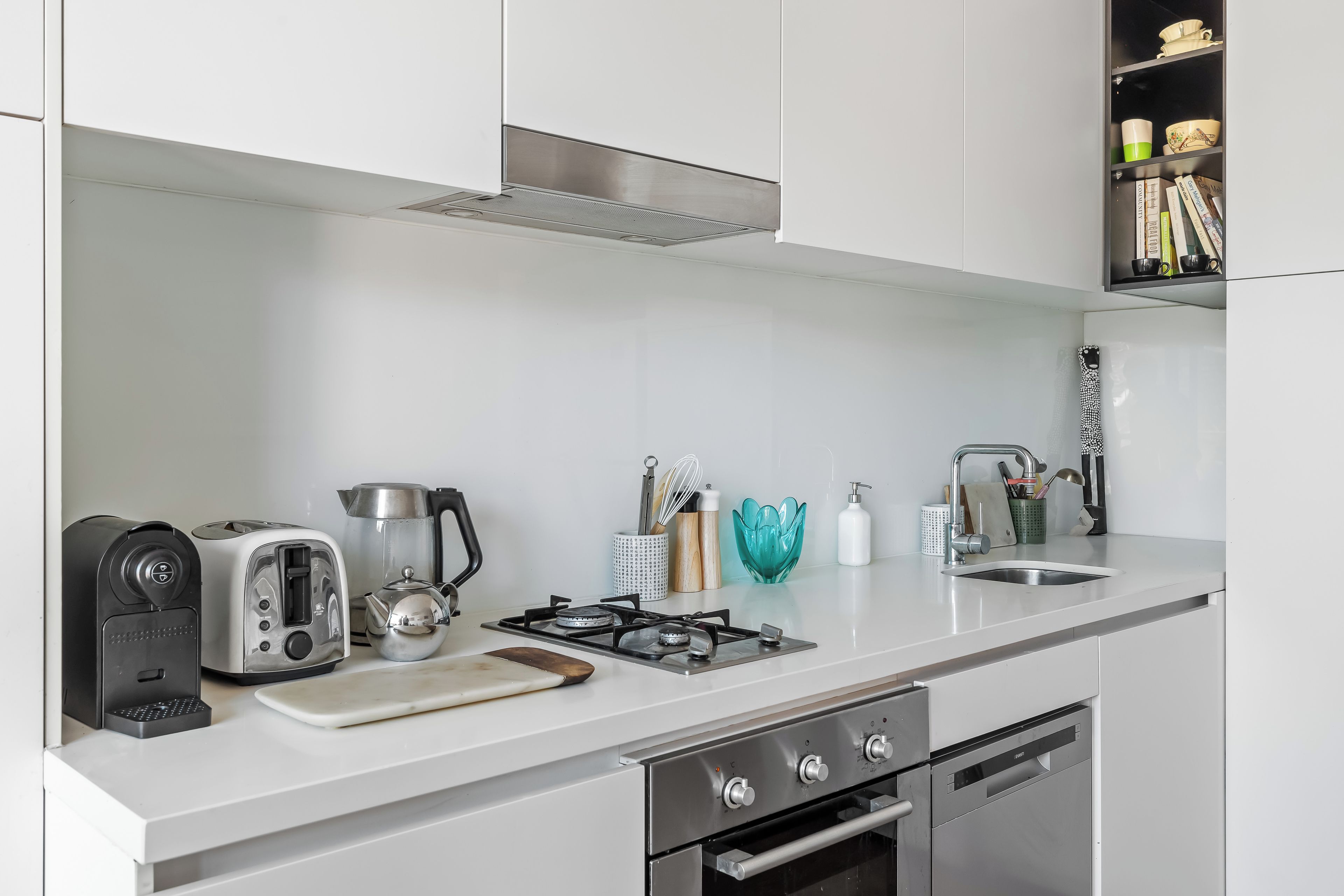 A modern kitchen with a gas stove, a coffee maker, a kettle, and a toaster.