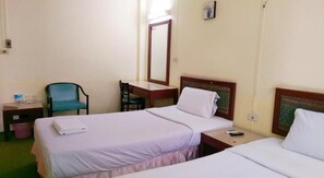 Une chambre d’hôtel avec deux lits simples, un bureau avec une chaise, une petite table et une poubelle.