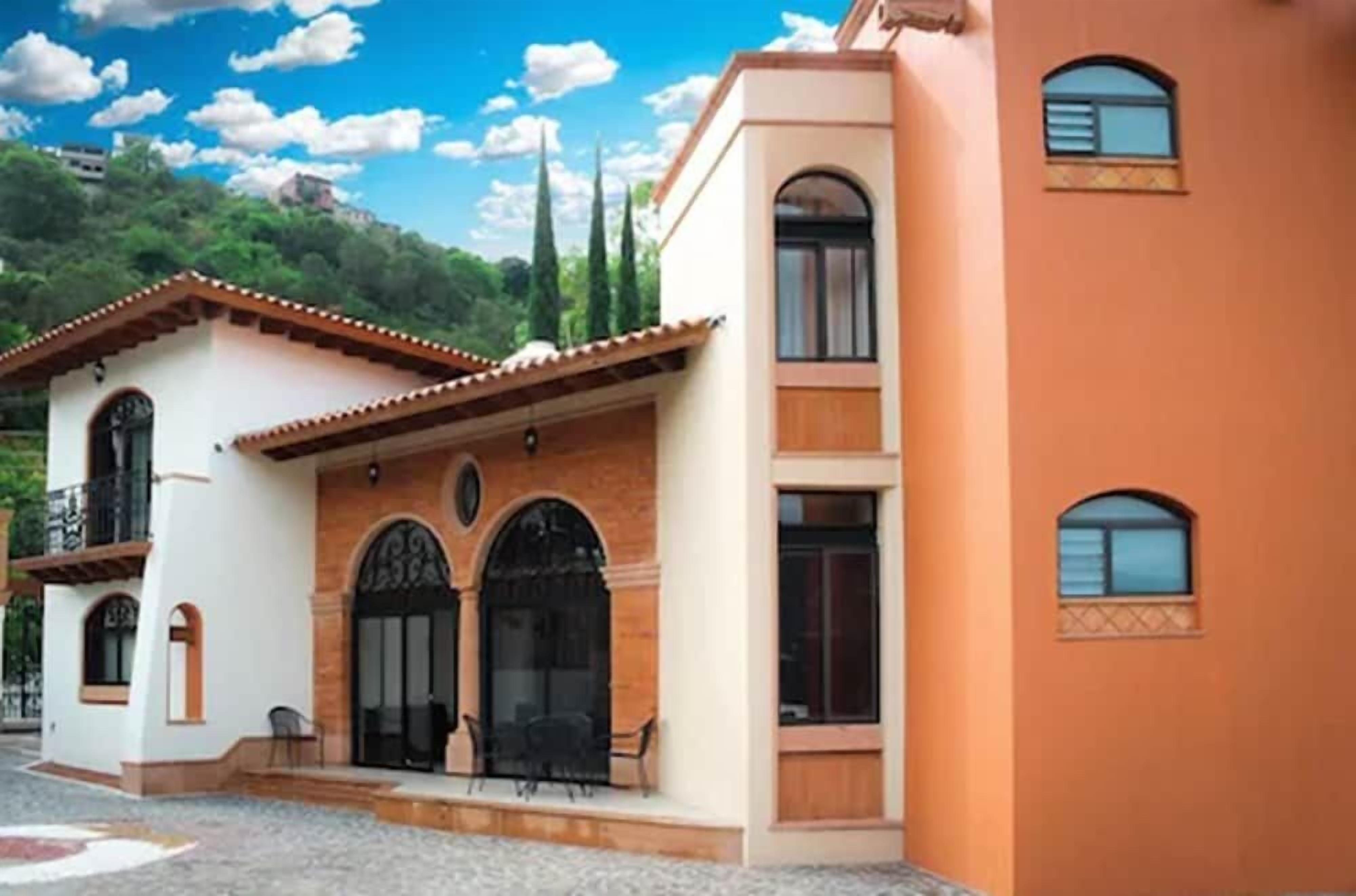 A two-story building with a balcony, arched windows, and a patio area.