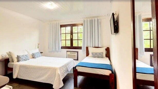 A room with two beds, a desk, a chair, and a TV mounted on the wall. - Pousada Sarata Tartaruga (Búzios)