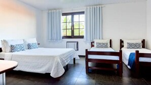 A room with two beds, a window with curtains, a radiator, and a tiled floor. - Pousada Sarata Tartaruga (Búzios)