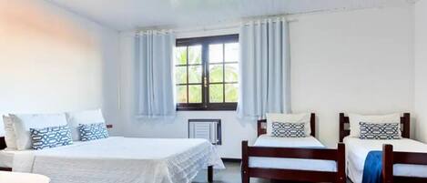 Una habitación con dos camas, una ventana con cortinas, un radiador y suelo de baldosas.