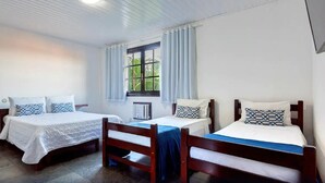 A room with two beds, a window with curtains, a radiator, and a ceiling light. - Pousada Sarata Tartaruga (Búzios)
