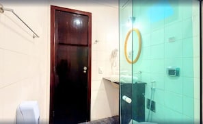 A bathroom with a dark wooden door, a glass partition, a mirror, and a toilet. - Pousada Sarata Tartaruga (Búzios)