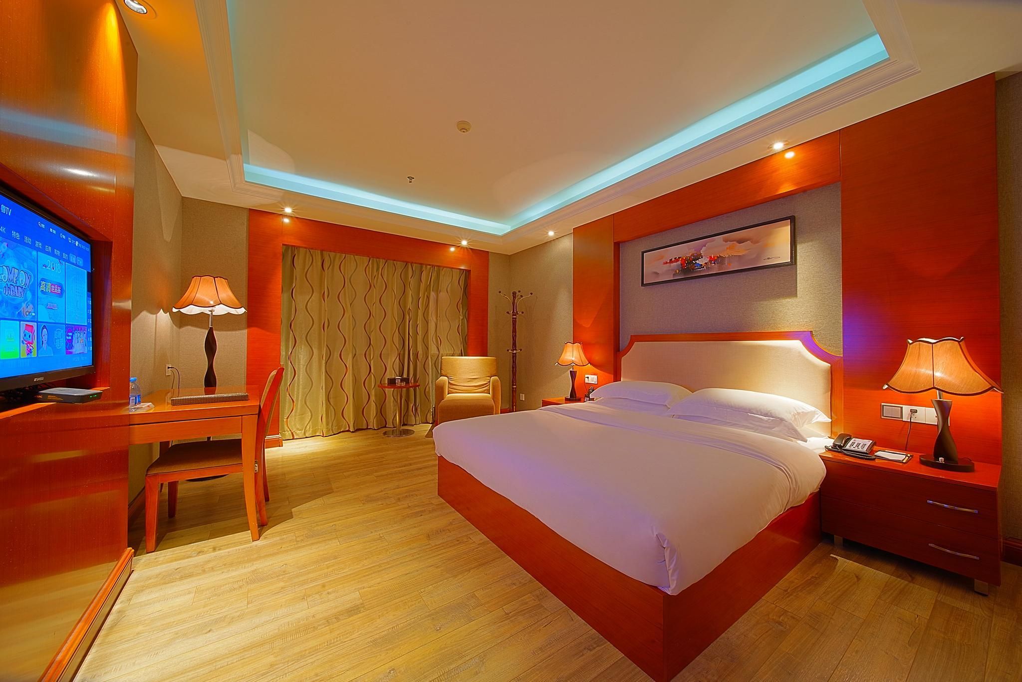Ein Hotelzimmer mit Bett, Schreibtisch, Stuhl, Fernseher und einem Bild an der Wand.