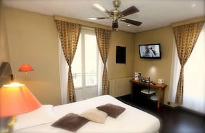 A hotel room with a bed, a desk, a television, and curtains. - The Originals City Hotel L Iroko Aix Les Bains Grand Port (Aix-les-Bains)