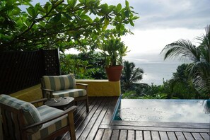 A wooden deck with a seating area, a potted plant, and a view of the ocean. - Belo Monte Hotel and Museum (Príncipe Island)