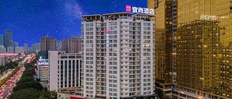 A high-rise hotel with multiple floors, surrounded by a cityscape with other buildings and a busy road.