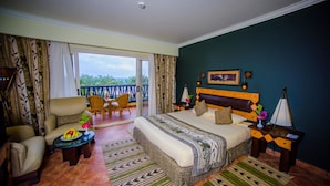 A hotel room with a bed, a seating area with chairs, a small table with fruit, and a view of the outdoors. - Carols Beau Rivage Matrouh (Marsa Matrouh)