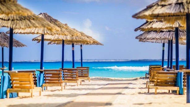 A beach with thatched umbrellas and wooden chairs. - Carols Beau Rivage Matrouh (Marsa Matrouh)