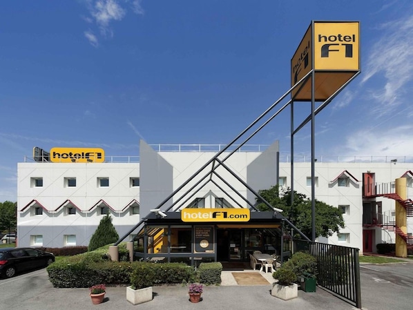 Un hotel de disseny modern, amb un cartell destacat de 'hotel F1', un senyal de lloc web i una entrada ben visible.