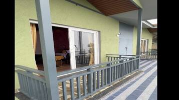 A building with a covered porch, a tiled walkway, and a door leading to an interior space.