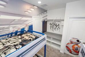 Ein Zimmer mit einem Etagenbett, einer Wand mit Star Wars-Kunstwerken und einem Star Wars-Spielzeug.