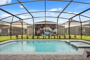 A swimming pool with a covered area and a mural of football players. - 8BR Windsor Cay villa with private pool, game room, sleeps 16 (Clermont)