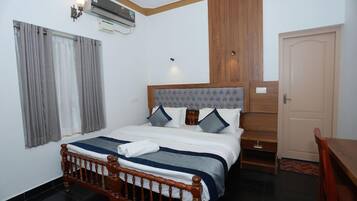 A bedroom with a wooden bed, grey curtains, a wooden headboard, and a white door.