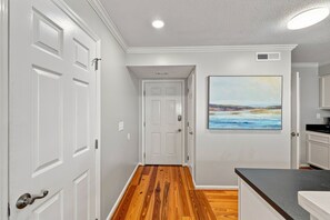 A hallway with white doors, a wooden floor, and a painting on the wall. - Direct Oceanfront Condo in the Heart of The Village. (St. Simons Island)