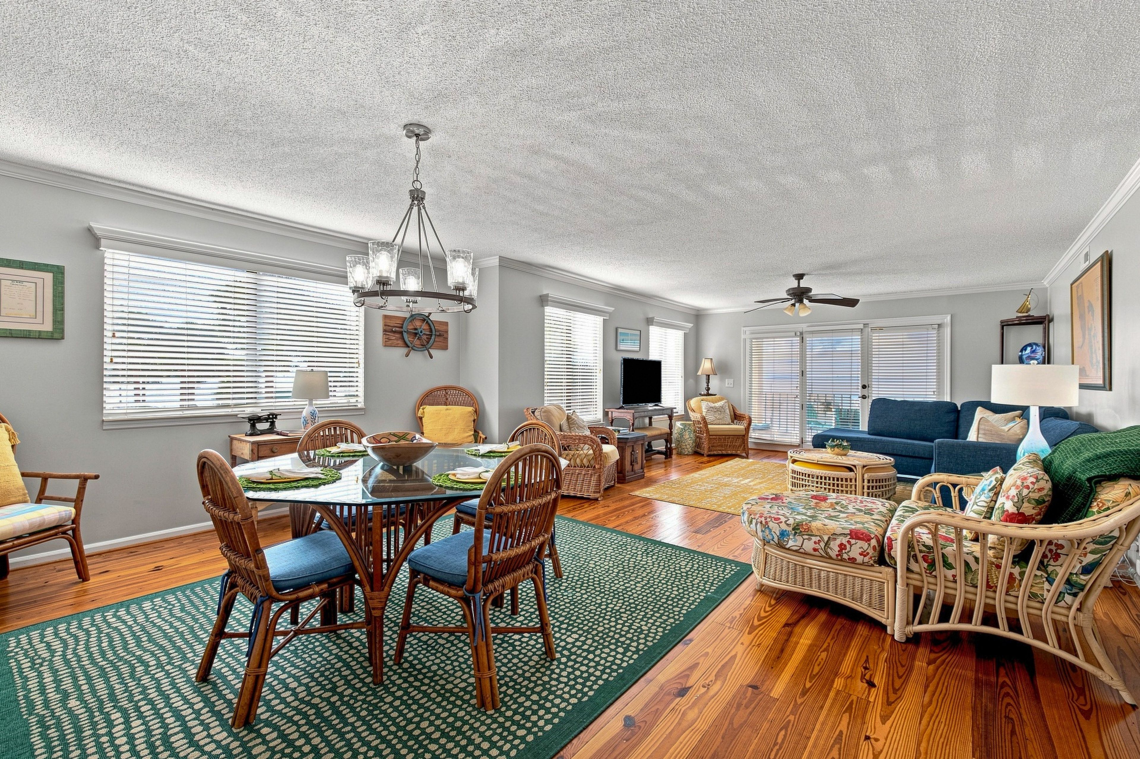 Ein geräumiges Wohnzimmer mit Essbereich, Holzboden und Deckenventilator.